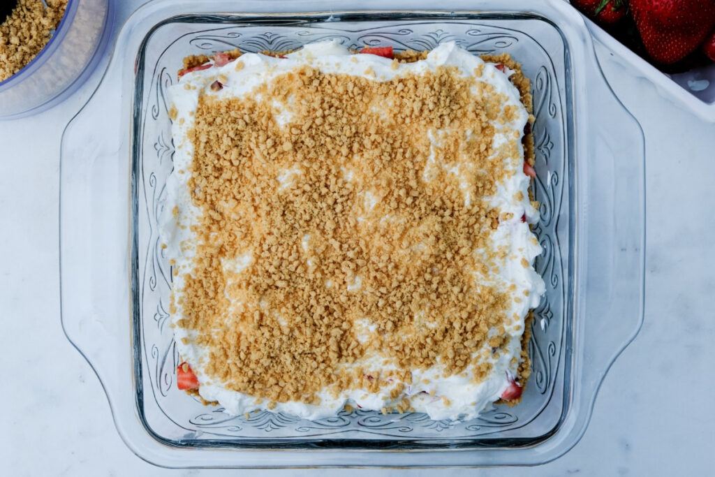 Cookie crumb layer over whipped cream when making a strawberry icebox cake. 