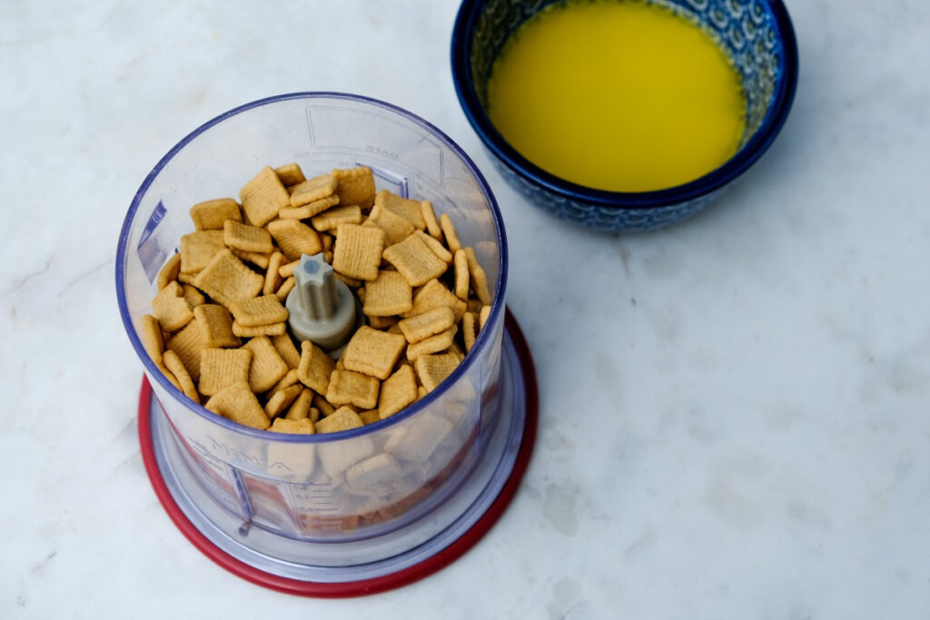 Catalina crunch cereal in a small food processor with melted butter on the side. 