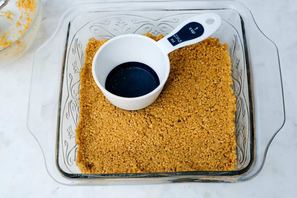 Preparing a crust in a small baking pan before adding the filling. 