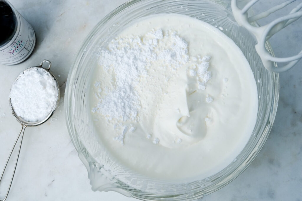 Homemade whipped cream in a clear mixing bowl. 