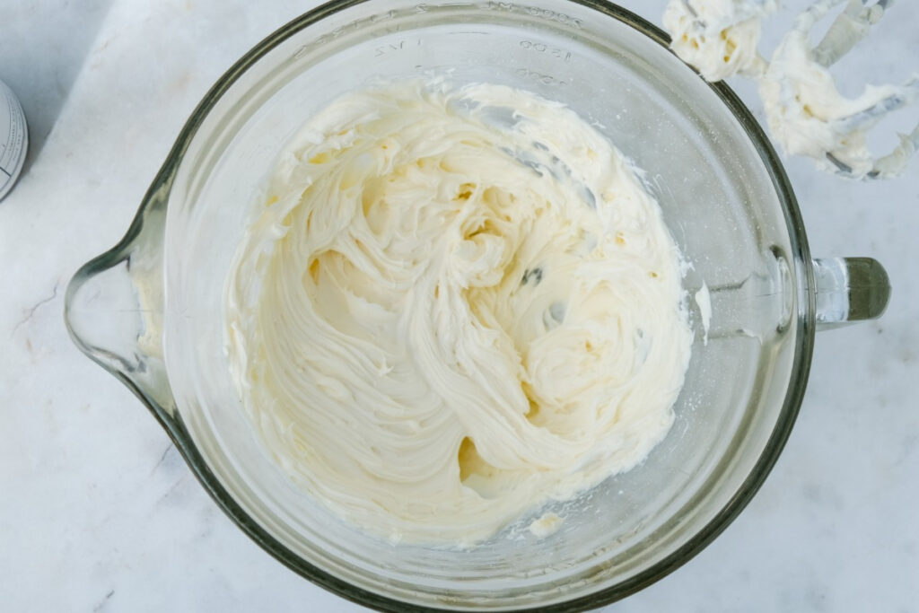 Cream cheese mixed with sugar in a clear mixing bowl. 