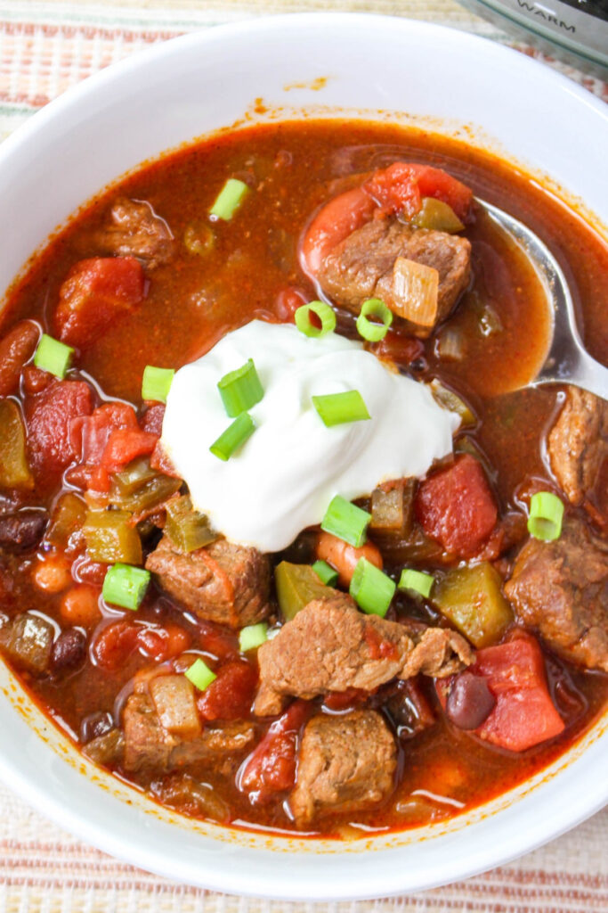 Top view of chili topped with sour cream and diced onion. 