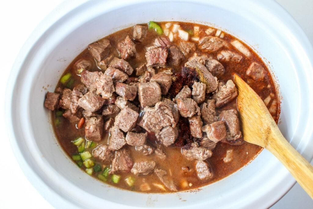 Cubed brisket added to slow cooker for chili recipe.