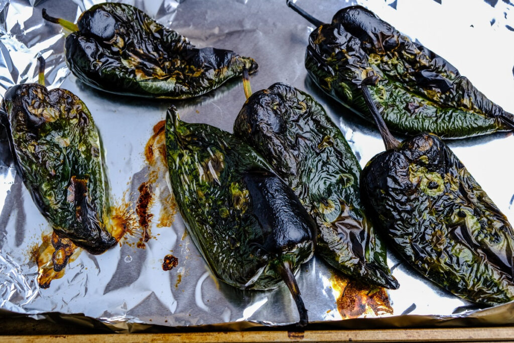 Poblano peppers on a baking sheet after under a broiler. 