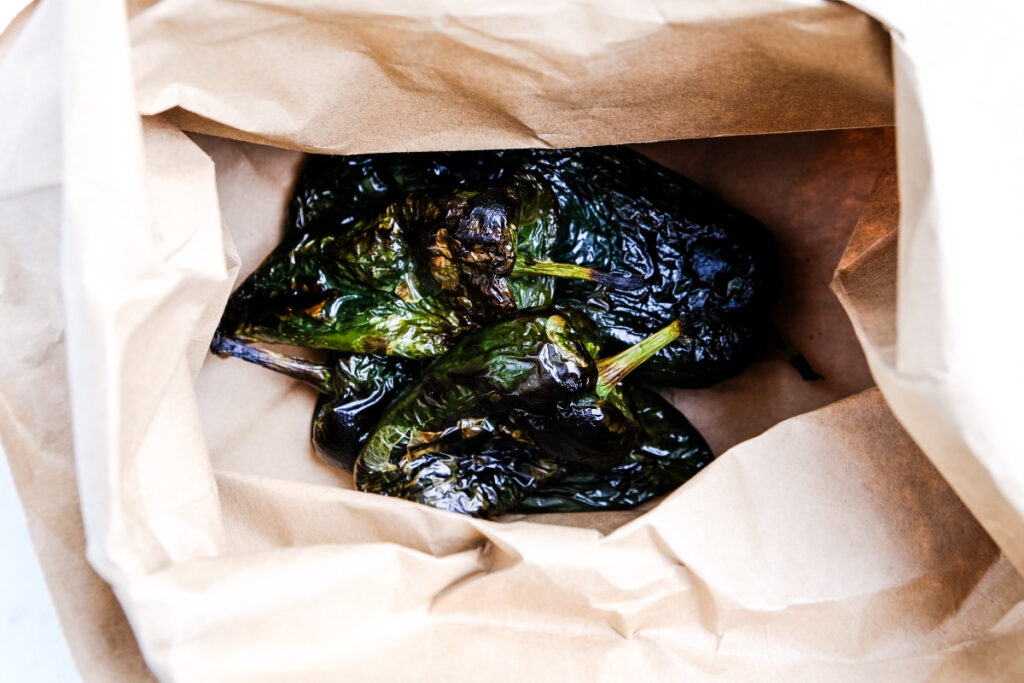 Charred poblano peppers  in a paper bag. 