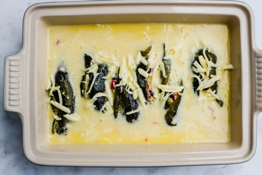 Egg mixture over stuffed chiles in a casserole dish. 