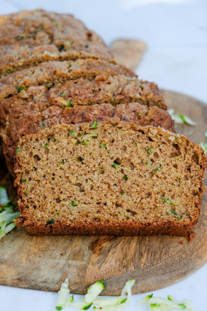 Sliced homemade zucchini bread on a wooden cutting board. 