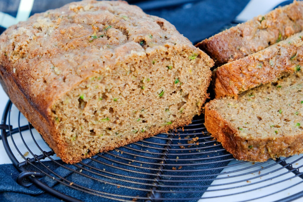 Baked zucchini bread sliced and placed on a cooling rack.