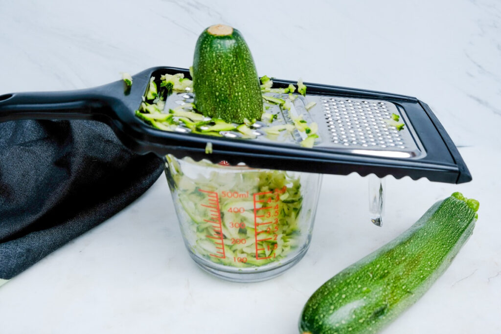 Shredded zucchini in a measuring cup. 
