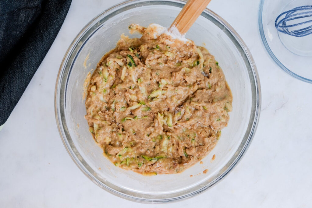 Wet and dry ingredients in a mixing bowl to make zucchini bread. 