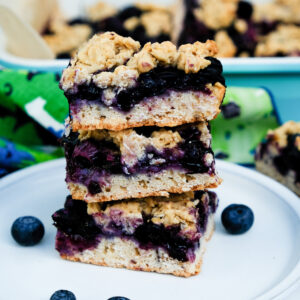 Blueberry oatmeal bars stacked on a white serving dish.