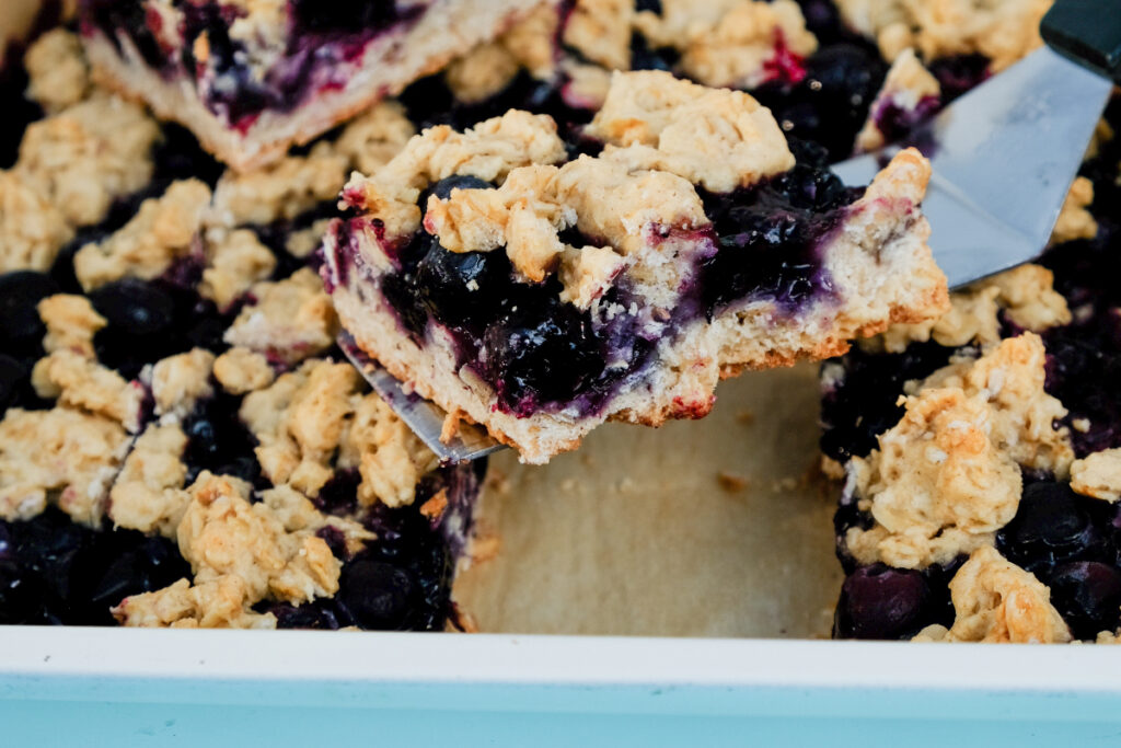 Slice blueberry bars in a blue baking dish. 
