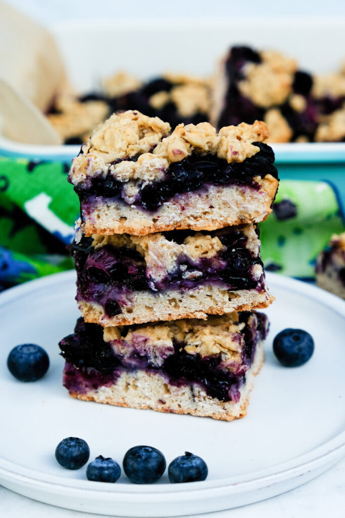 A stack of blueberry oatmeal bars on a white serving plate. 