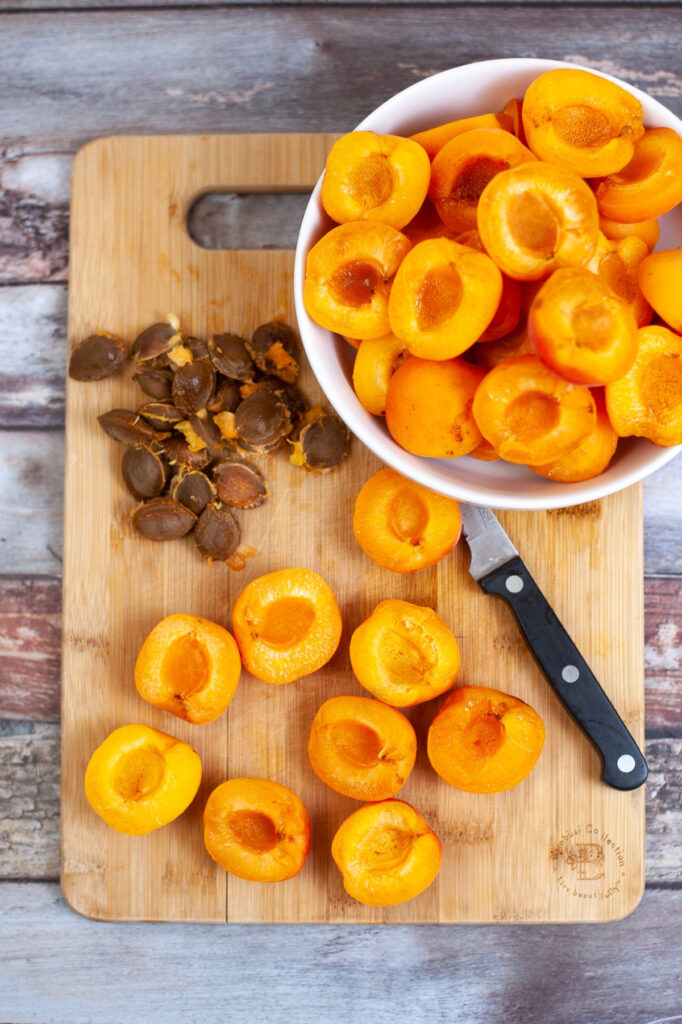 Apricots on a cutting board sliced in half with the pits removed.