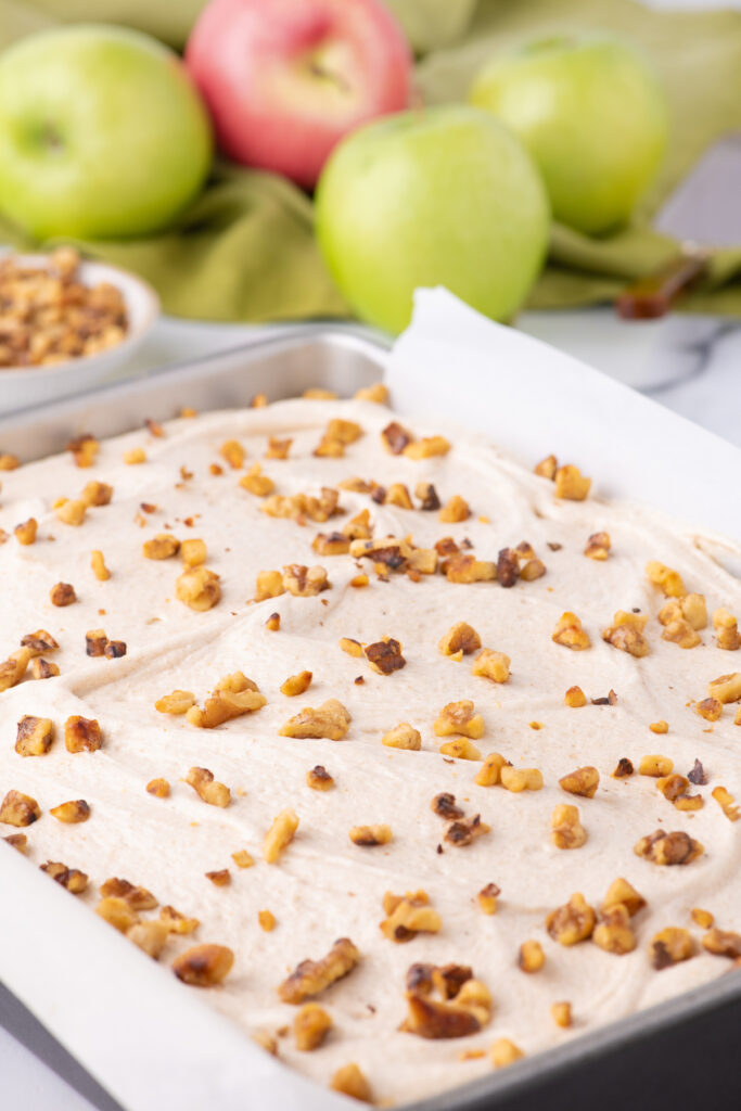 A full cake in a cake pan topped with chopped nuts.