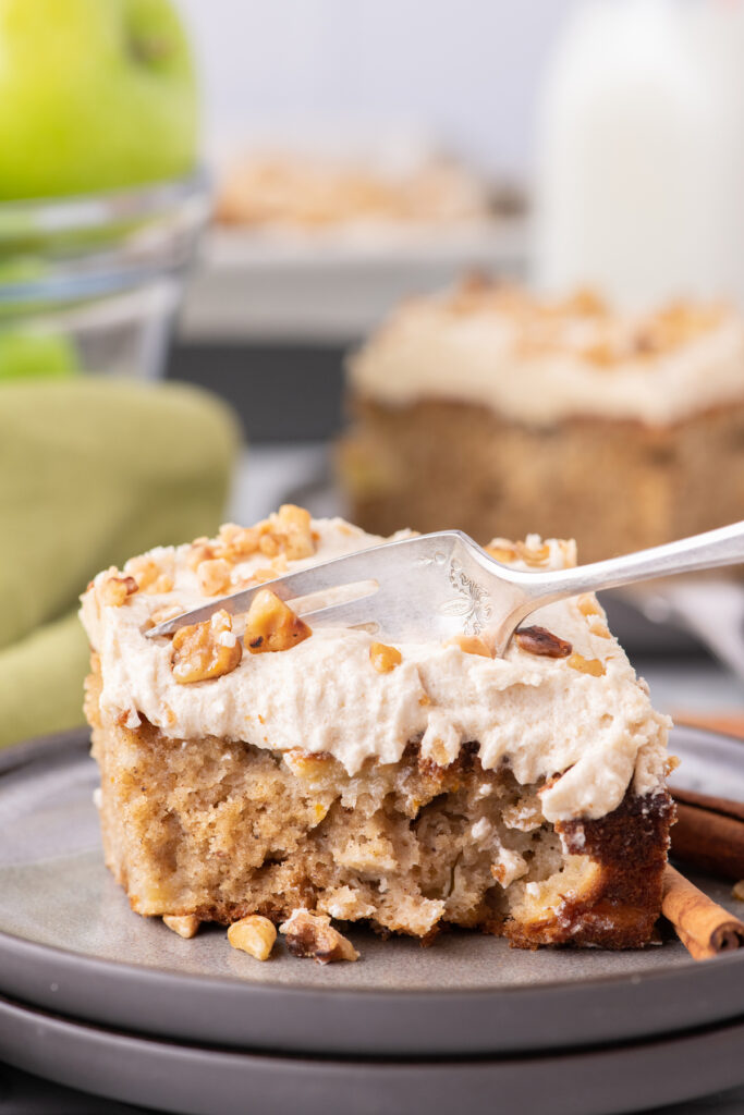 A fork digging into a piece of homemade cake with buttercream frosting.