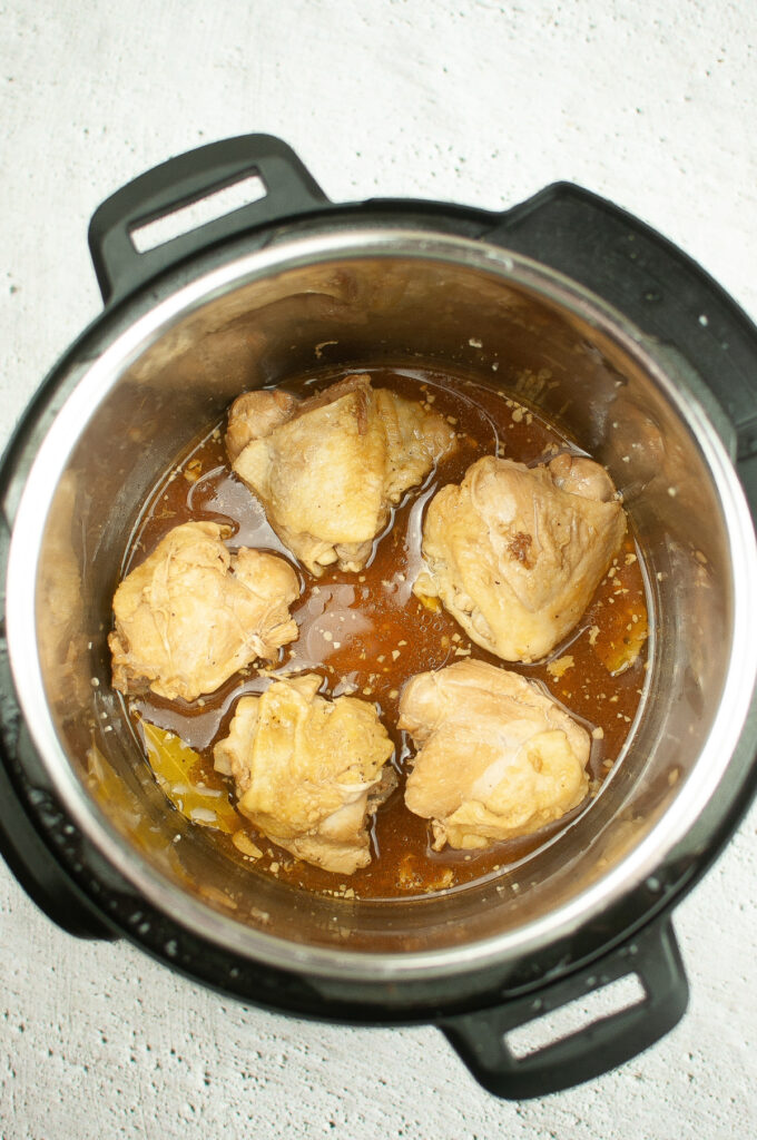 Chicken in an Instant Pot cooking in a sauce. 