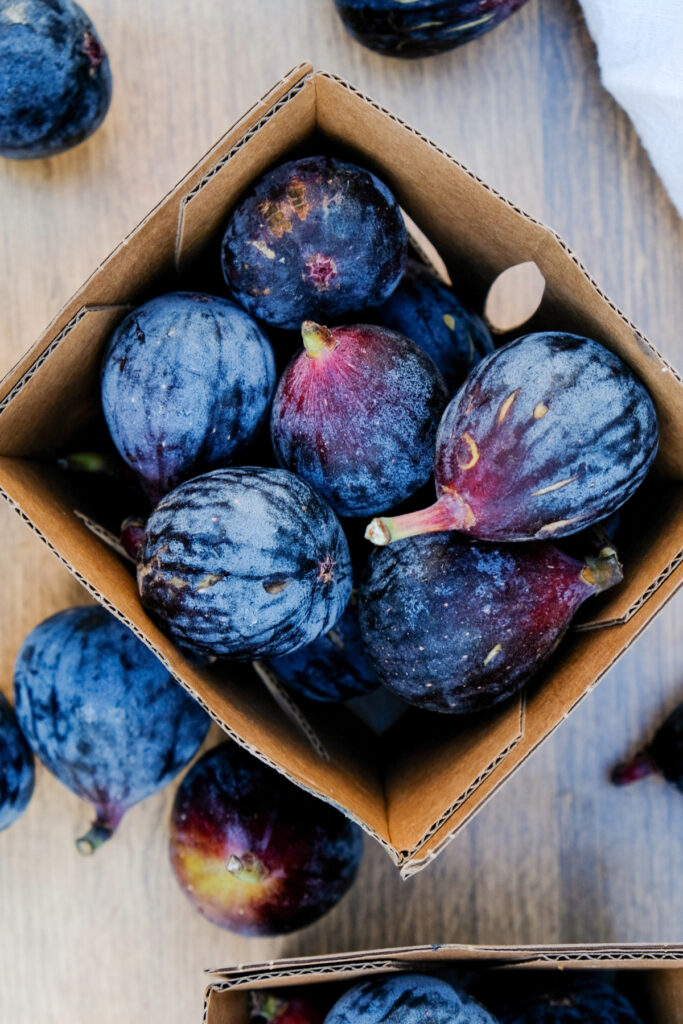 Top view of fresh mission black figs in a brown cardboard basket.