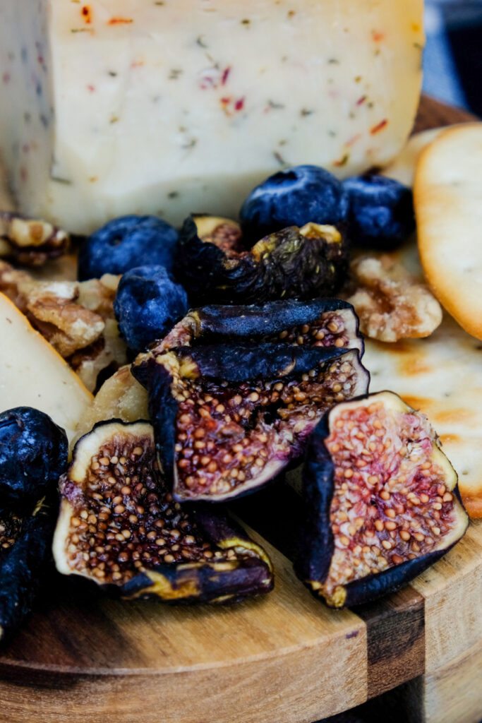  A close view of dehydrated figs on a small cutting board with cheese on the side.