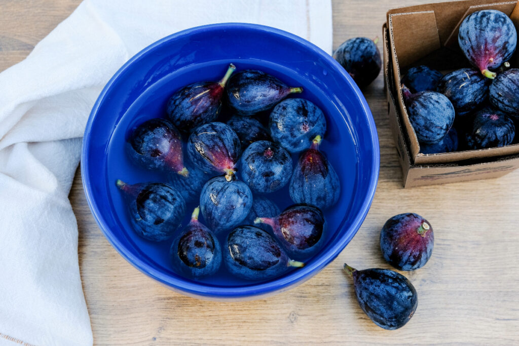 Fresh figs in a blue bowl in water to clean. 