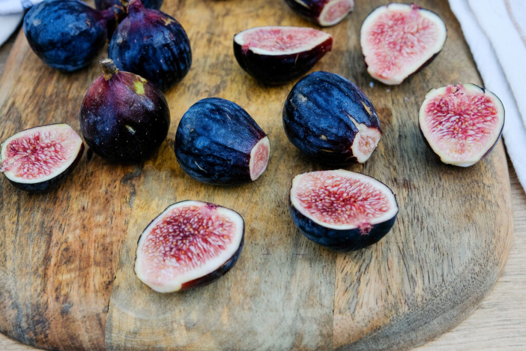 Fresh figs sliced in half on a brown cutting board. 