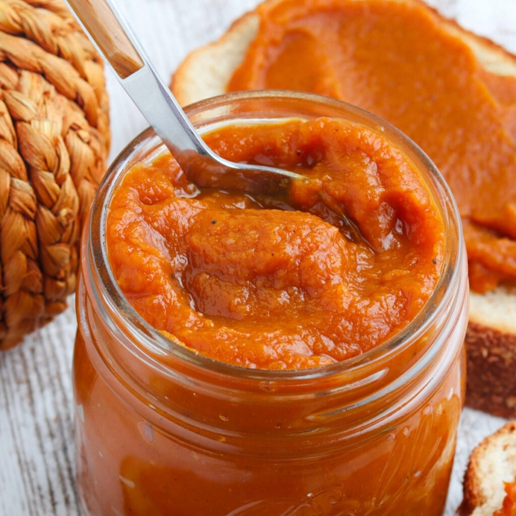 Spoon placed in a clear Mason jar filled with homemade pumpkin butter.