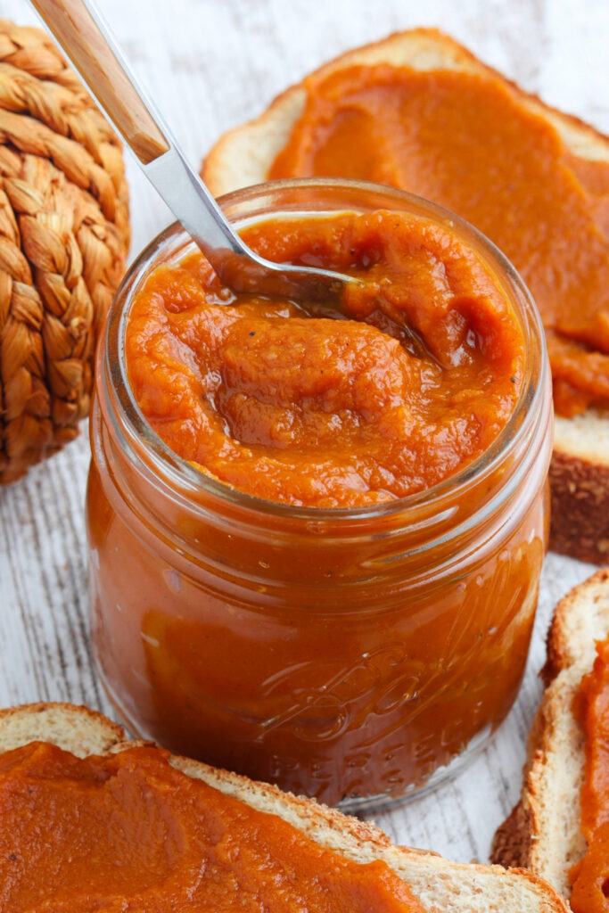 Toast on a side of a mason jar filled with pumpkin butter. 