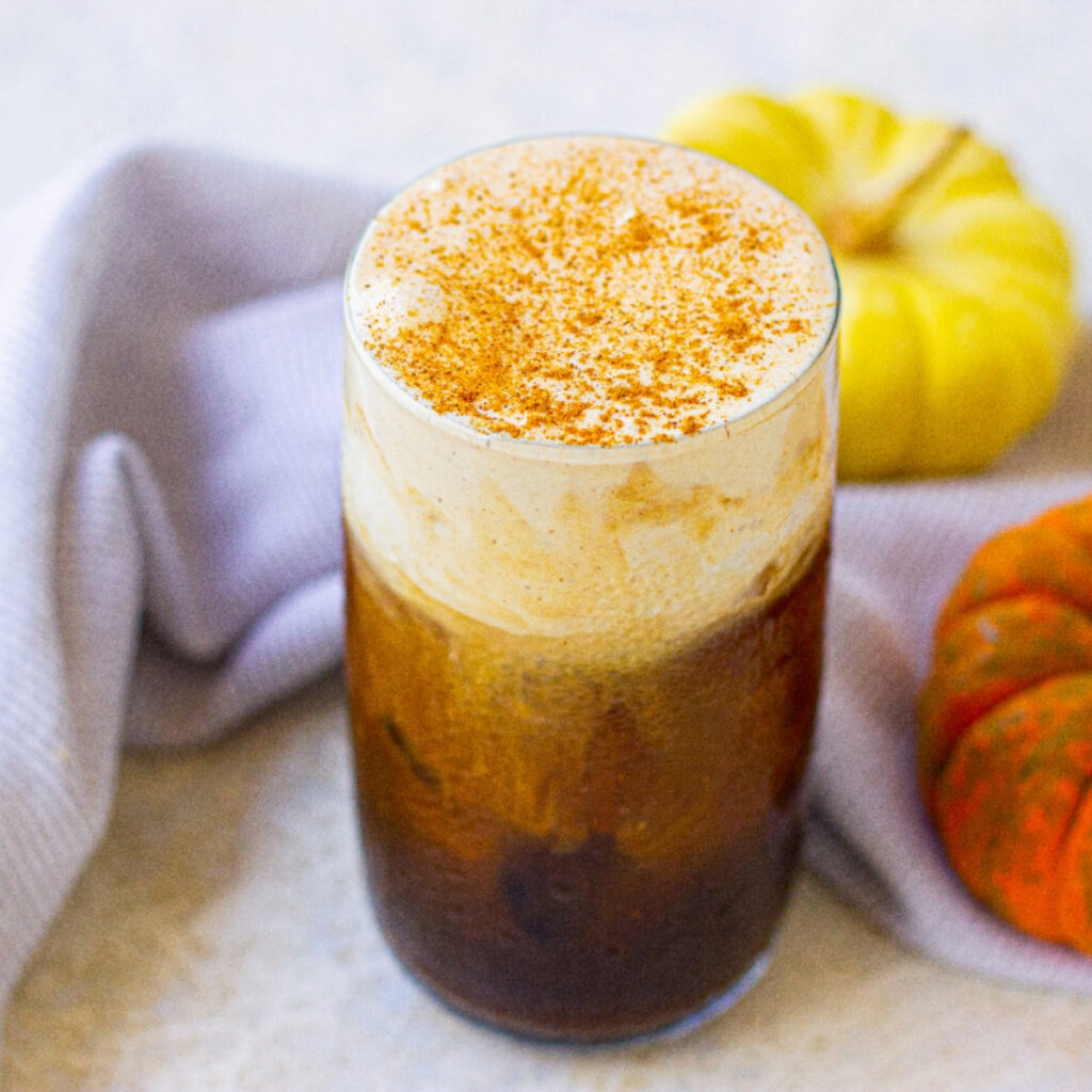 Pumpkin cream cold brew beverage in a clear glass.
