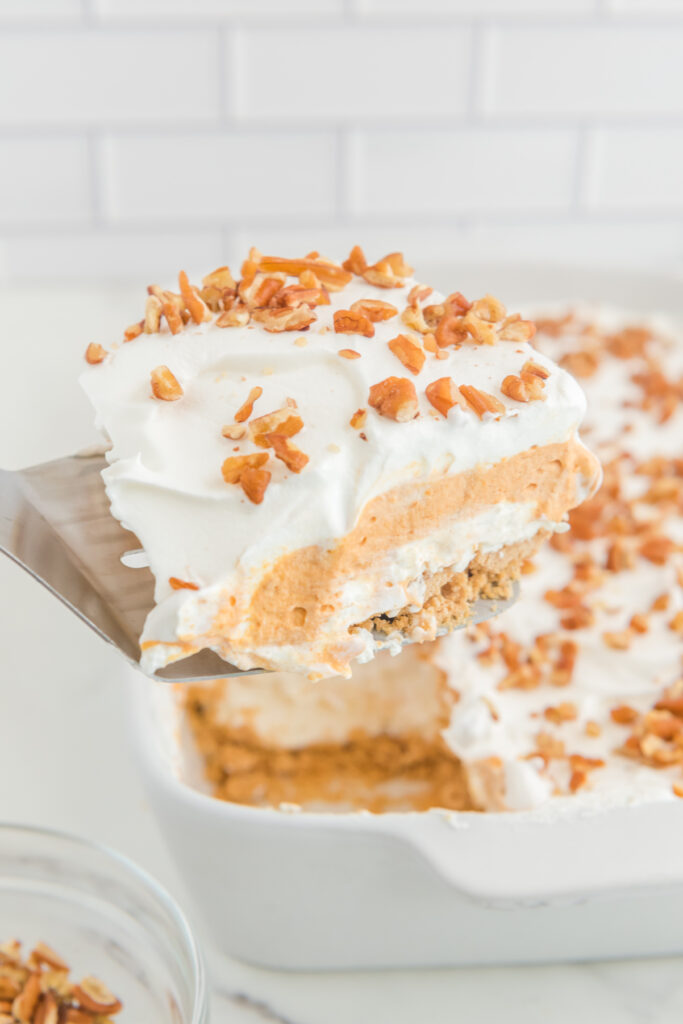 A spatula picking up a slice of pumpkin layered dessert.