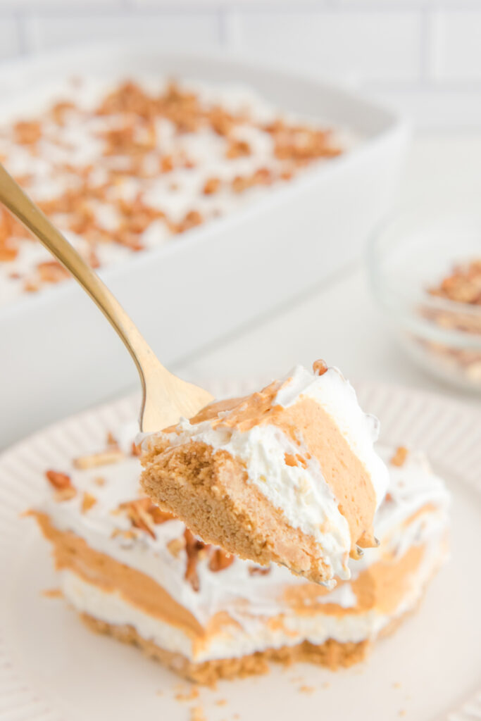 A forkful of pumpkin layered dessert over a white plate.