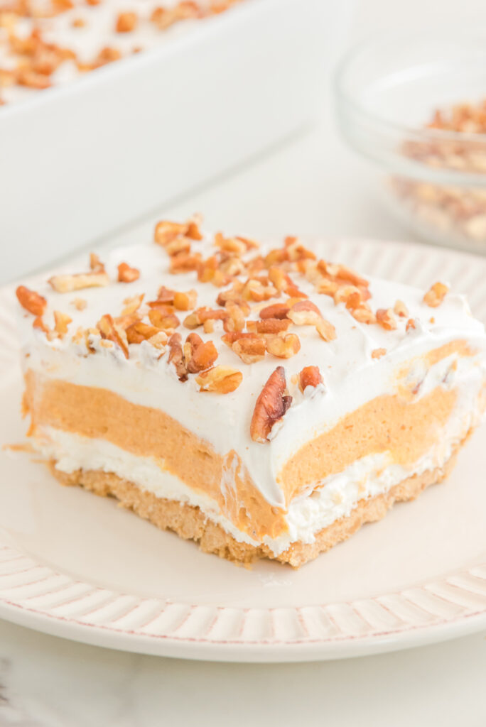 A slice of pumpkin layered dessert on a white serving plate. 