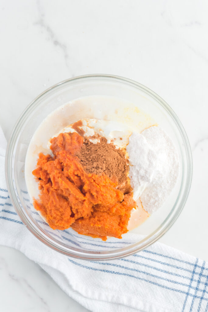 Pumpkin mix with spices and whipped cream in a mixing bowl.