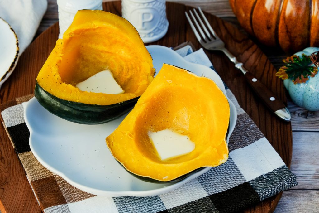 Instant Pot acorn squash with melted butter on a serving plate ready to eat. 