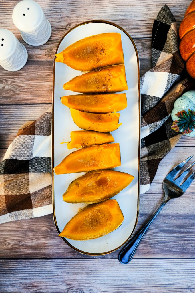 Overhead view of cooked acorn squash on a white serving plate. 