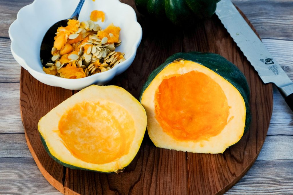Whole acorn squash cut in half with the seeds removed. 