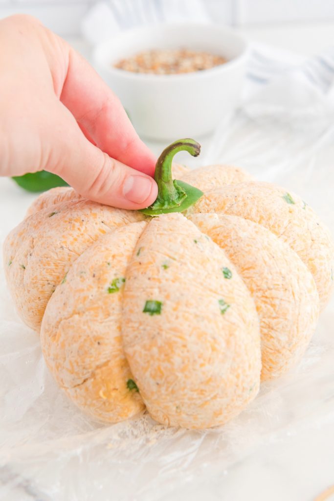 Adding a stem to a pumpkin shaped cheese ball.