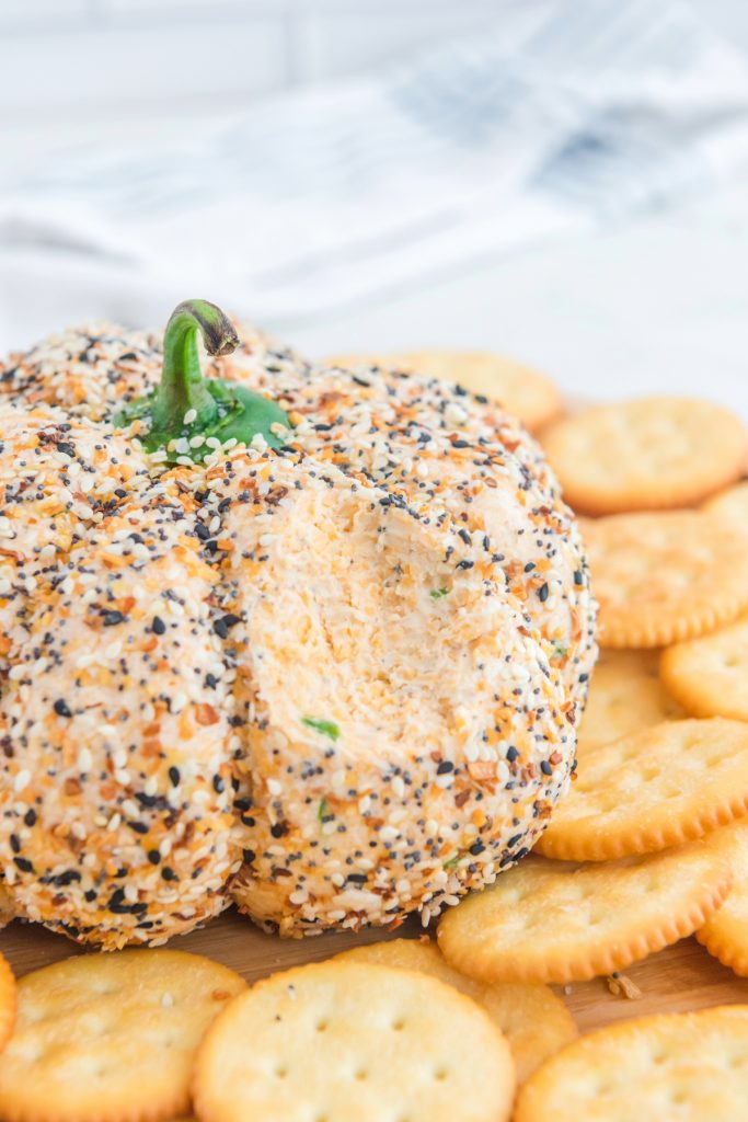 Cheese ball with a portion removed with a cracker. 