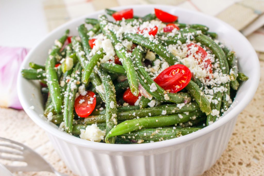 Green beans with tomatoes in a white serving bowl.