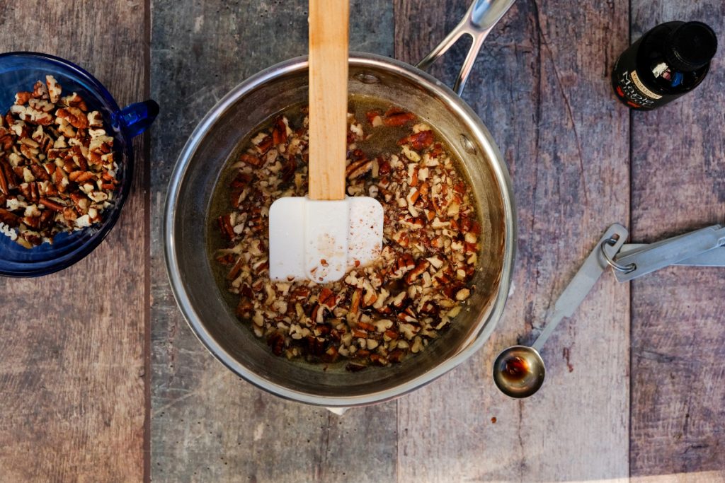 Pecans and maple extract added to the sugar mix in a saucepan.