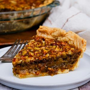 A slice of homemade pecan pie on a white plate.