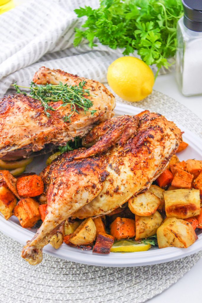 Cooked chicken with diced potatoes on a white serving platter.