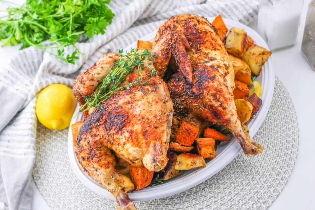 Chicken dinner with vegetables on a white serving plate. 