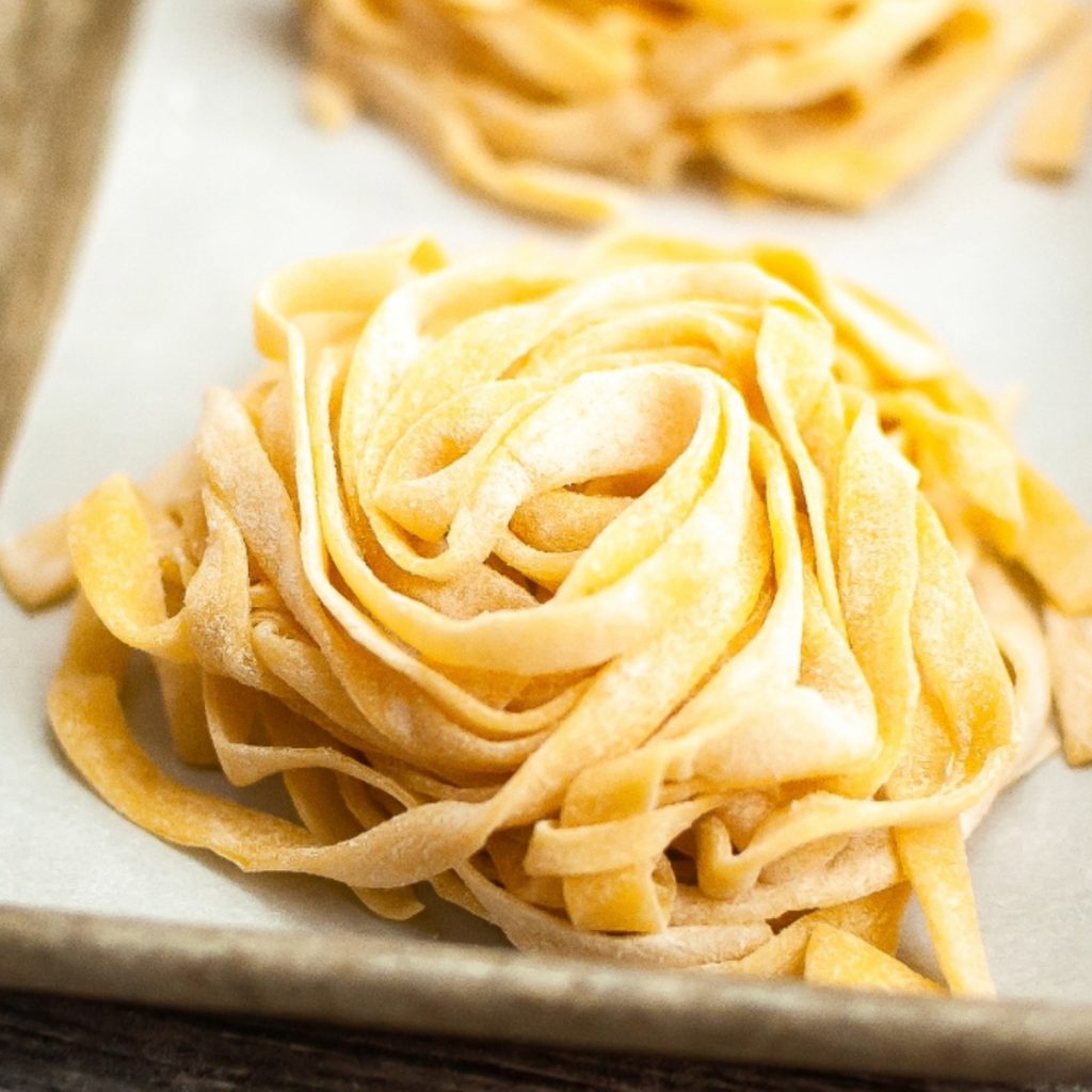 Fresh homemade pasta sliced and placed on parchment paper.