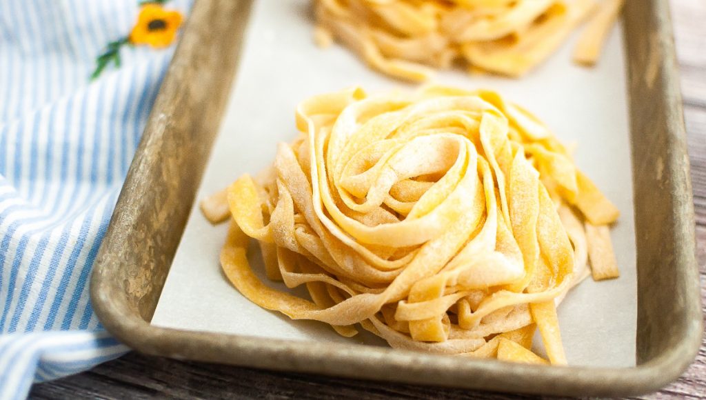 Fresh cut homemade pasta on a tray before cooking. 