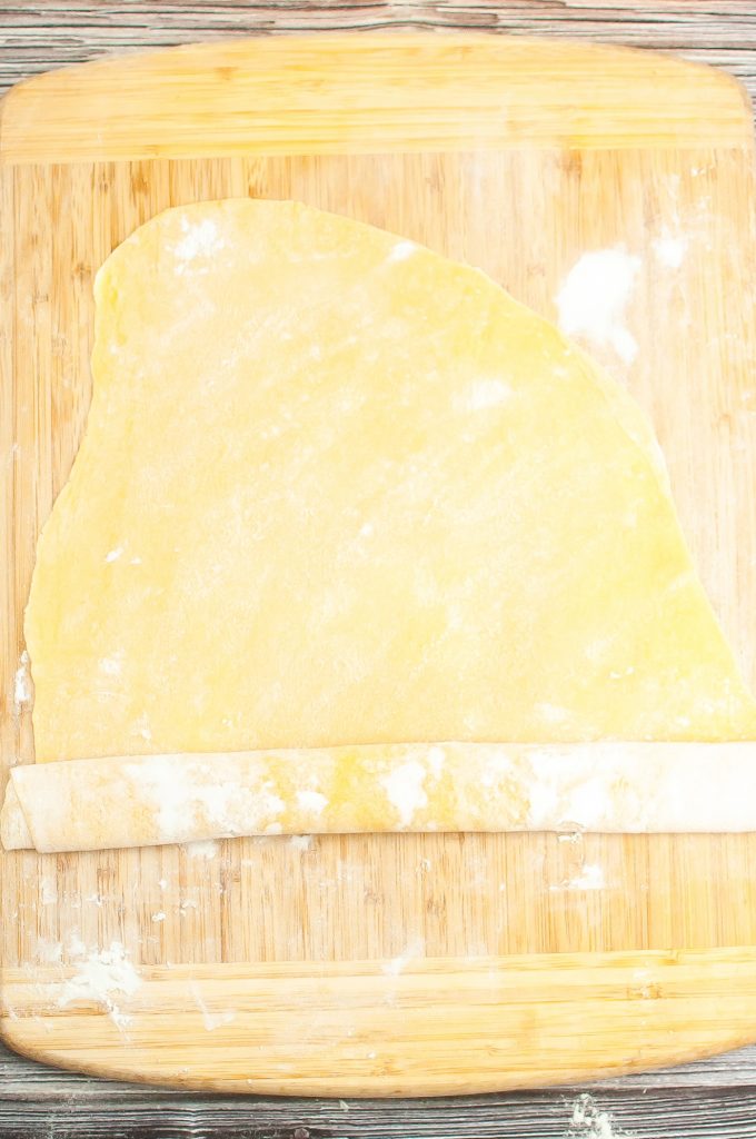 Pasta dough rolled on a cutting board.