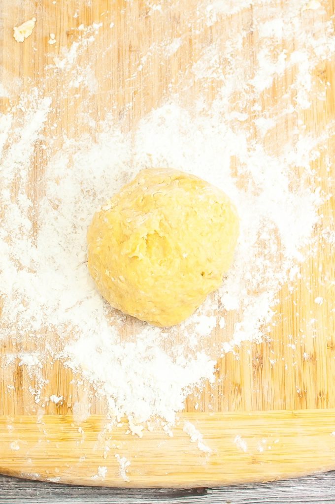 Pasta dough on a cutting board rolled in a ball.