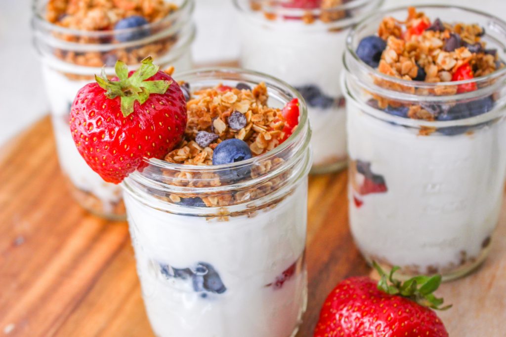 Mason jars layered with fruit between yogurt and granola. 