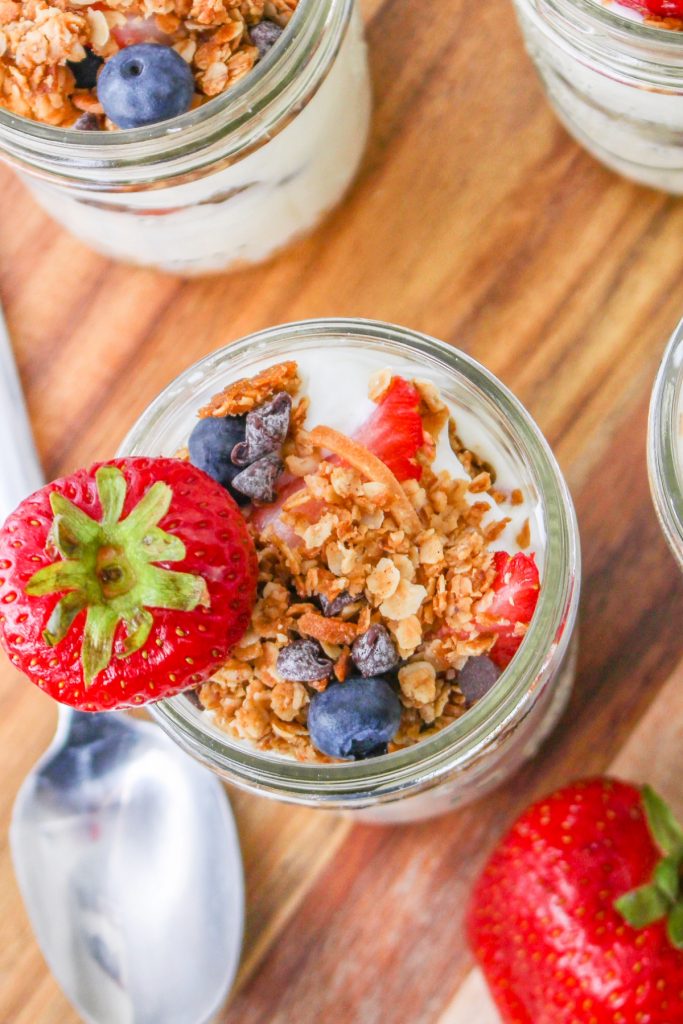 Top view of yogurt parfaits with a spoon on the side with fresh strawberries. 