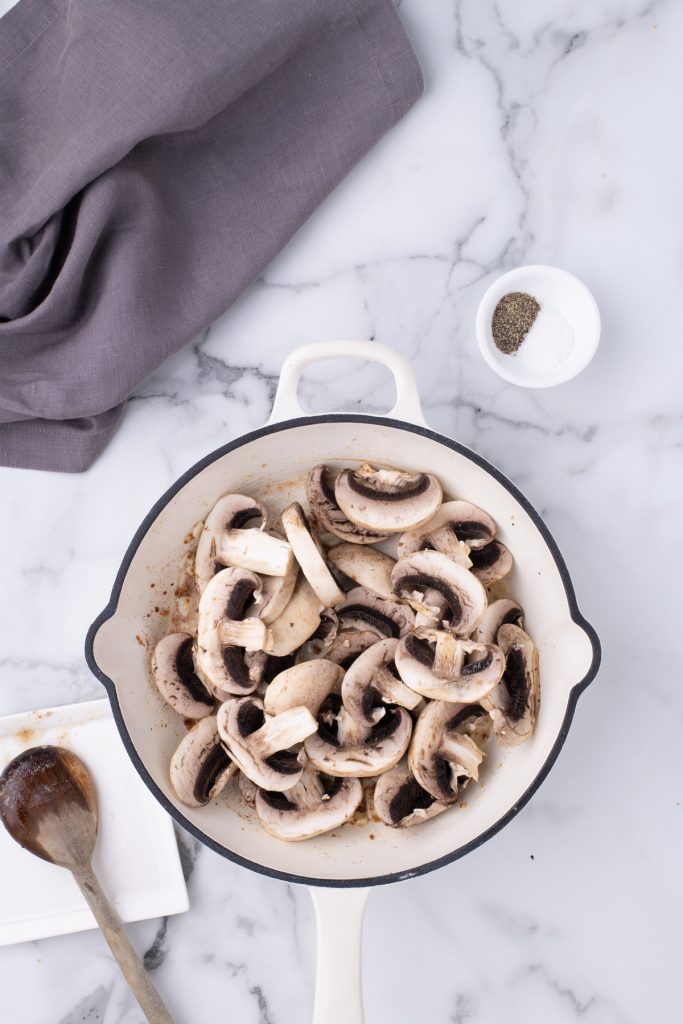 Raw sliced mushrooms in a skillet before cooking. 