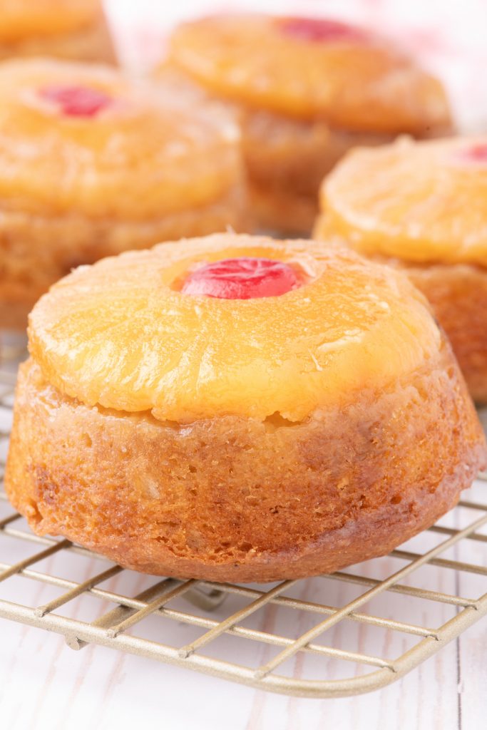 Mini pineapple upside down cakes cooling on a baking rack. 